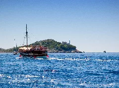 Boat With Tourists And Island With A Lighthouse